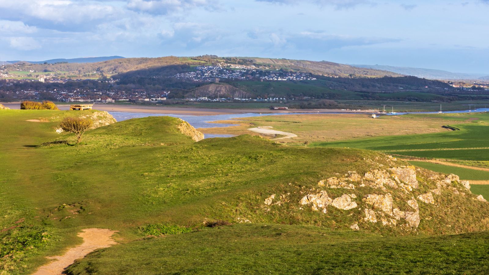 View from the top of a headland looking back inland with an estuary and hills in the background